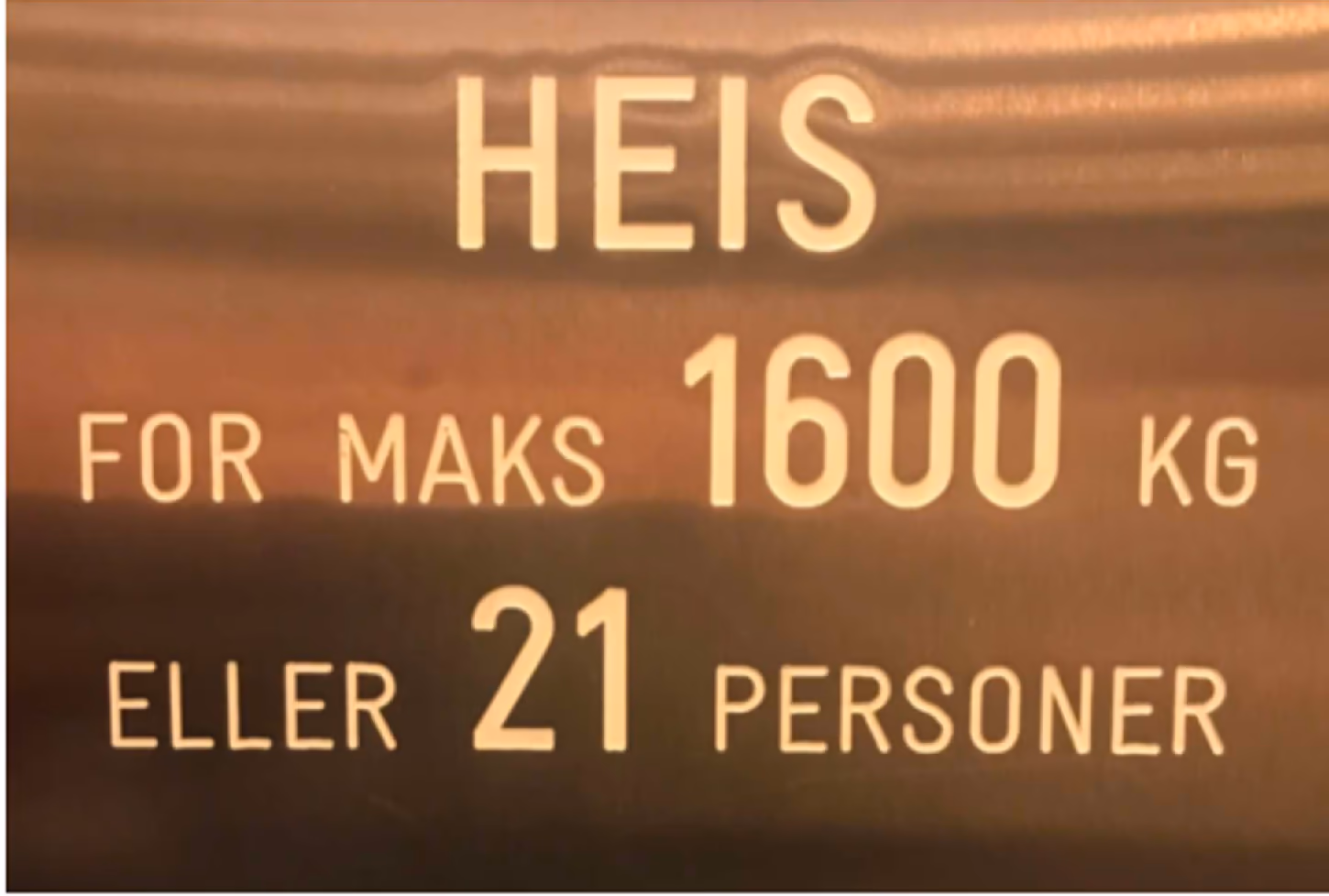 Skilt med teksten 'HEIS for maks 1600 kg eller 21 personer', og to tegnseriefigurer som diskuterer skiltet